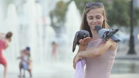 Attractive young woman feeding pigeons in the park