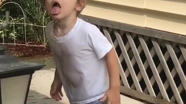 Little boy tries to drink sprinkler water trips on green house