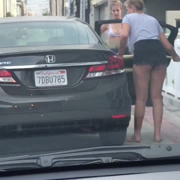 Two girls put surfboard in back seat