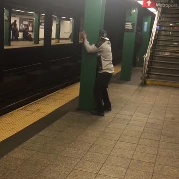 Guy hat backwards face between green pillar subway