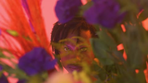 Gay boy looking straight through flowers