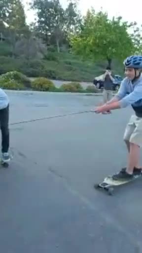 Two teens on skateboard hold on to white jeep