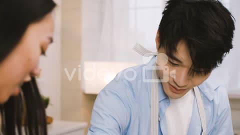 Close Up View Of A Japanese Man Wearing An Apron While Cooking And Talking With A Friend In The Kitc