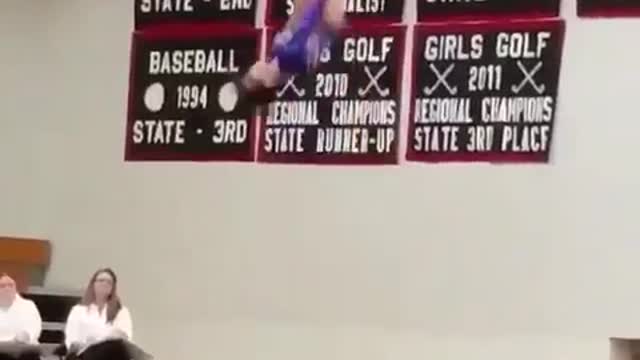 Girl in grey gymnastics suit does flips on trampoline competition and flies off