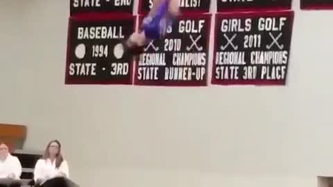 Girl in grey gymnastics suit does flips on trampoline competition and flies off