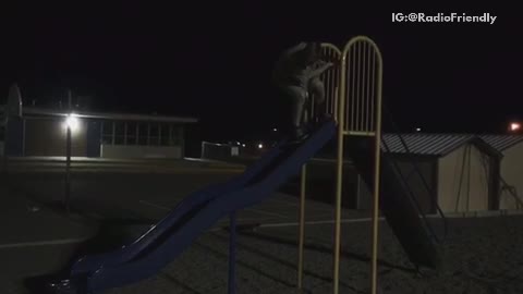 Kid tries to skateboard down blue slide falls down at night