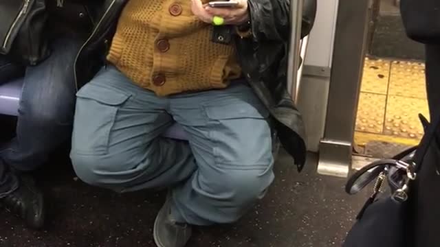 Guy wears bowler cap and bright shiny glasses on train