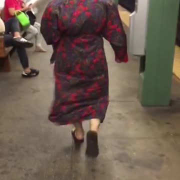 Bald person red headphones bathrobe walking subway platform station