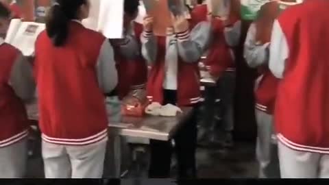 Before lunch,Chinese students are reading aloud in the school cafeteria