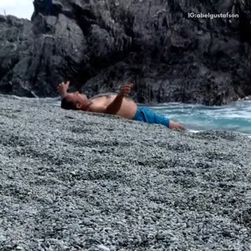 Man blue shorts throws sand on himself