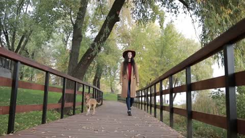 Fashionable woman walking the dog in public park