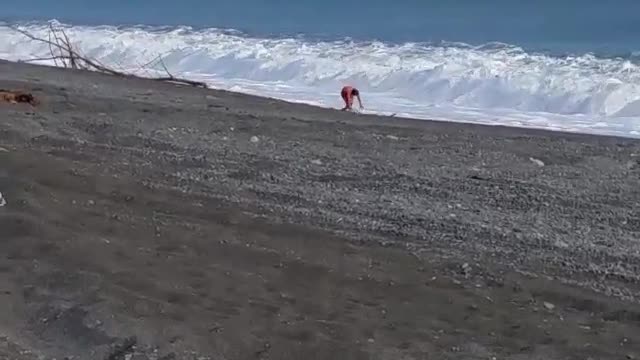 Man with green boogie board knocked down by wave