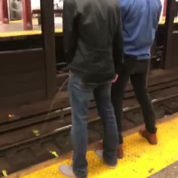 Two guys peeing on subway rail
