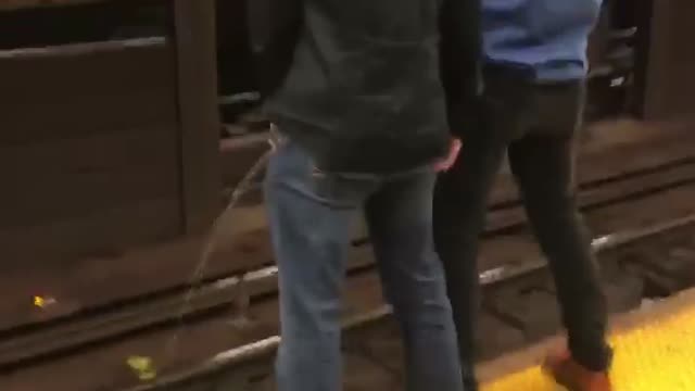 Two guys peeing on subway rail