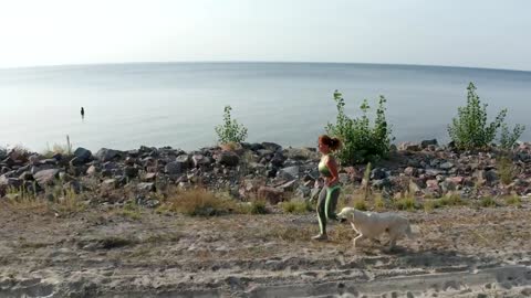 Young woman running with her dog near a coast