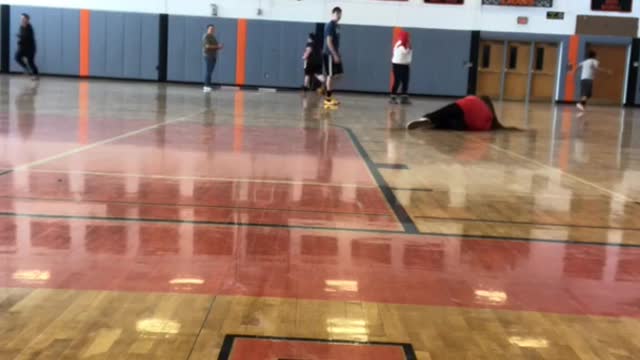 Girl kicks ball inside of gym, trips over her feet and falls hard