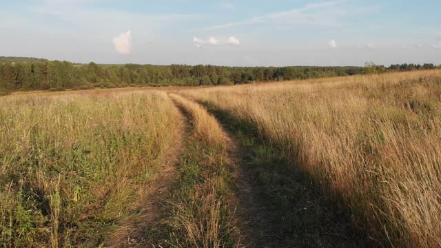 A drone flies over a road in a field.