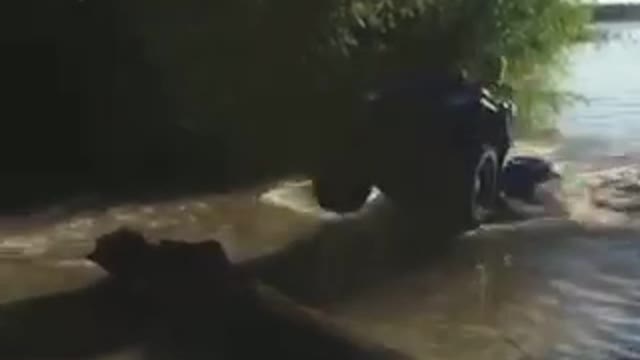 Guy riding atv four wheeler in shallow river