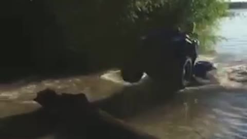 Guy riding atv four wheeler in shallow river