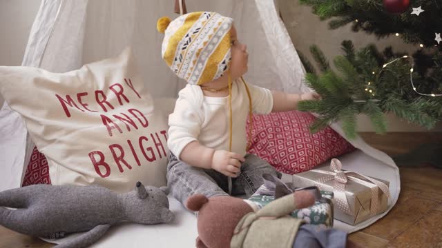 Funny Baby playing beside a Christmas tree