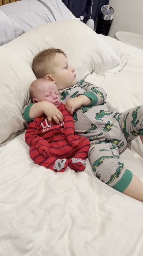 Big brother adorably cuddles with newborn baby