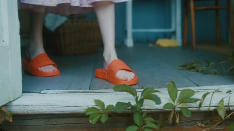 A Female Person Wearing Slides Standing at a Doorway