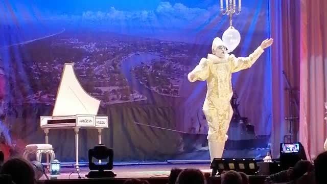 A juggler plays the piano with glasses in his mouth.