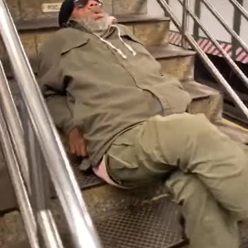 Man in green track suit laying on stairs