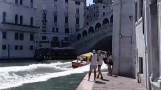 Yellow boat drives through canal quickly creates waves wets side walks