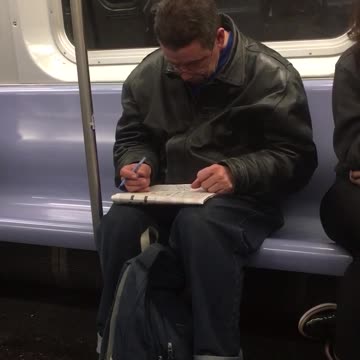 Guy green jacket subway notebook cleaning ears pen