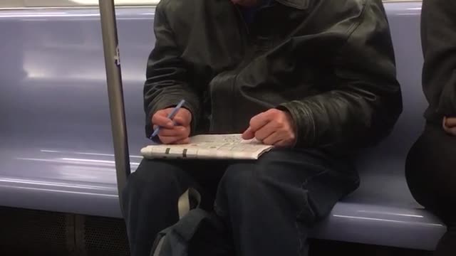 Guy green jacket subway notebook cleaning ears pen
