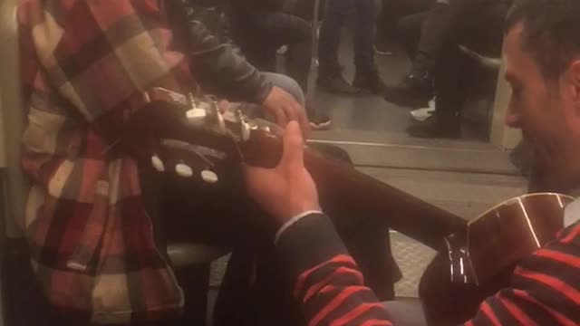 Old sunglasses man sings with guitar on subway