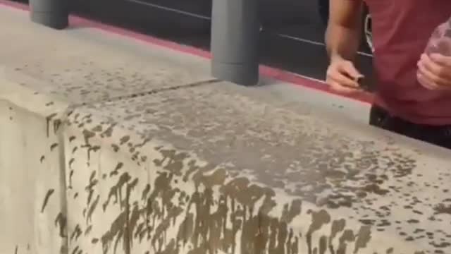 Men pour water from a bottle on the wall of the dam and it rises upwards