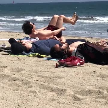 A guy laying on beach doing ab work out