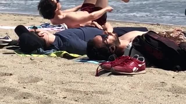 A guy laying on beach doing ab work out