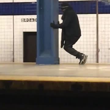 Man in black outfit does weird shin workout on subway platform