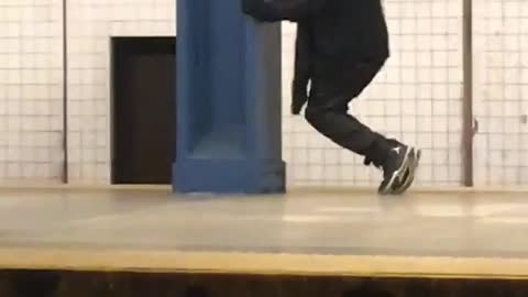 Man in black outfit does weird shin workout on subway platform