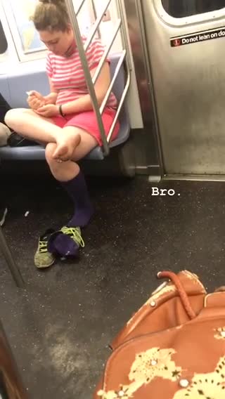 A woman in pink with her bare foot out on subway train