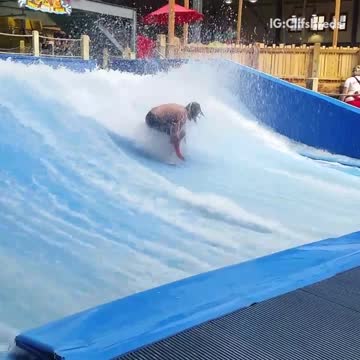 Long haired man falls off artificial surf machine