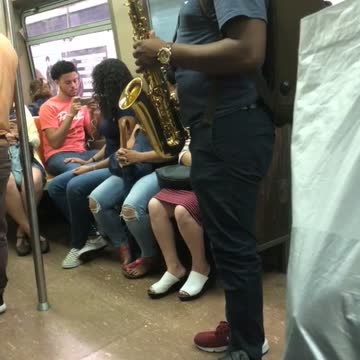 Guy green backpack playing saxophone on subway train