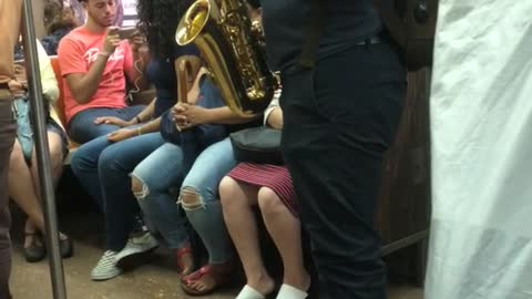 Guy green backpack playing saxophone on subway train
