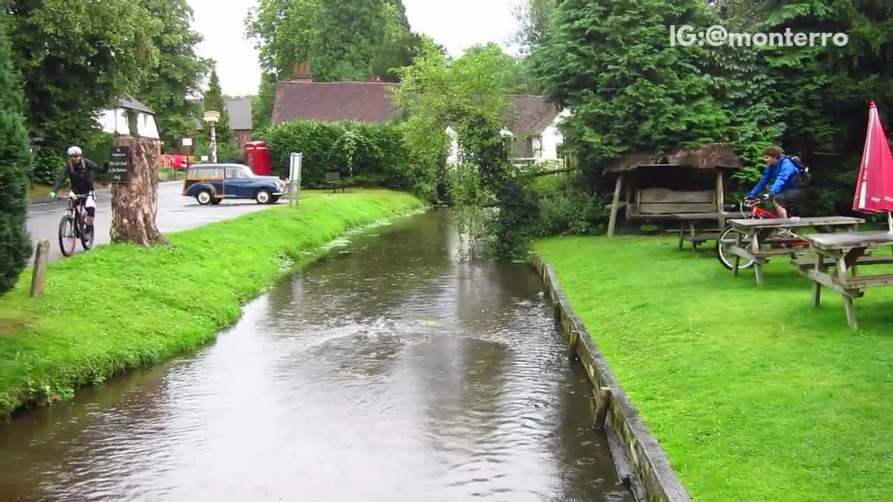 Guy in blue jacket on red bike falls into stream