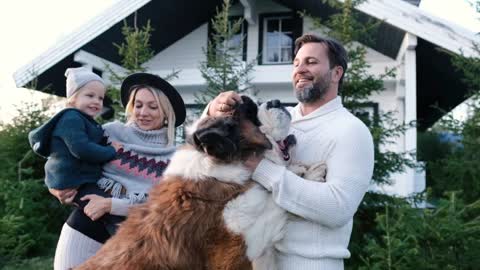 Happy family with their big dog near the house in nature