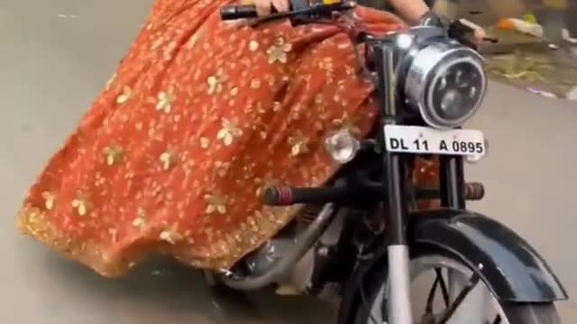 The girl of India country while running on the road while driving a bullet.