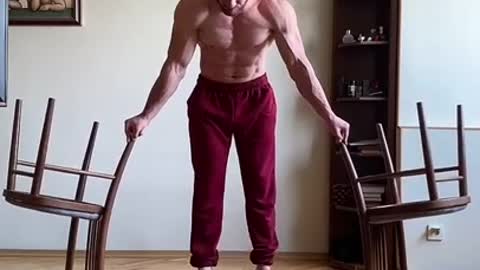 Guy Lifts Himself After Balancing His Hands Over Two Upside Down Chairs