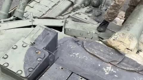 Ukrainian soldiers climb into a Russian tank