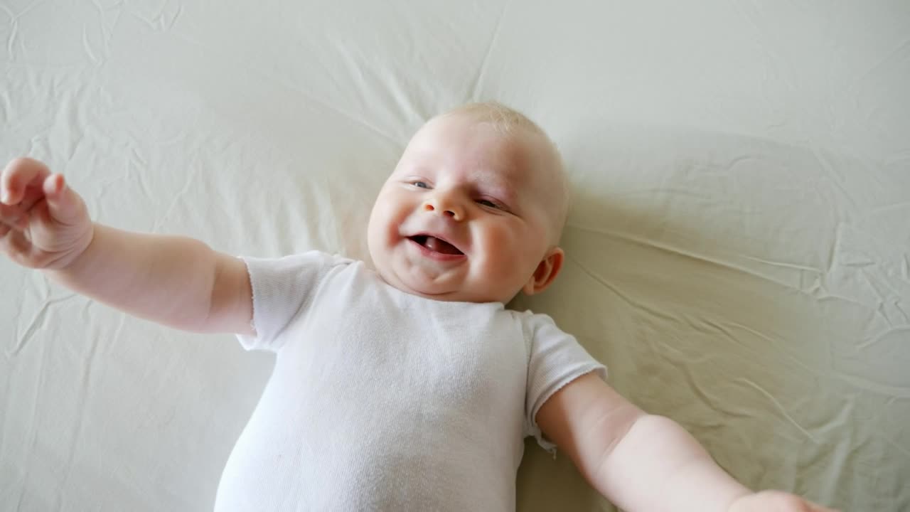 New baby boy laughing on bed