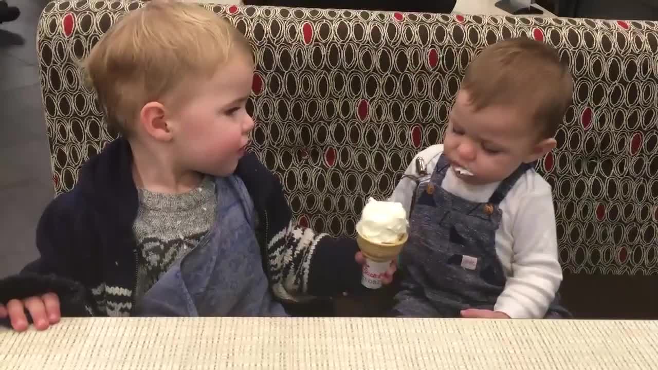 Toddler Slyly Attempts to Lick Ice Cream Cone in Elder Brother's Hand