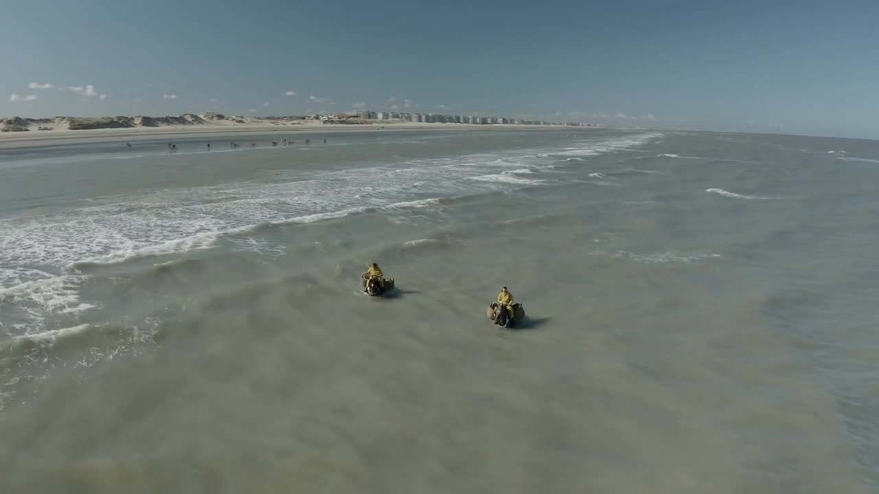 Aerial view of persons riding a horse along the shore in the water near Koksijde