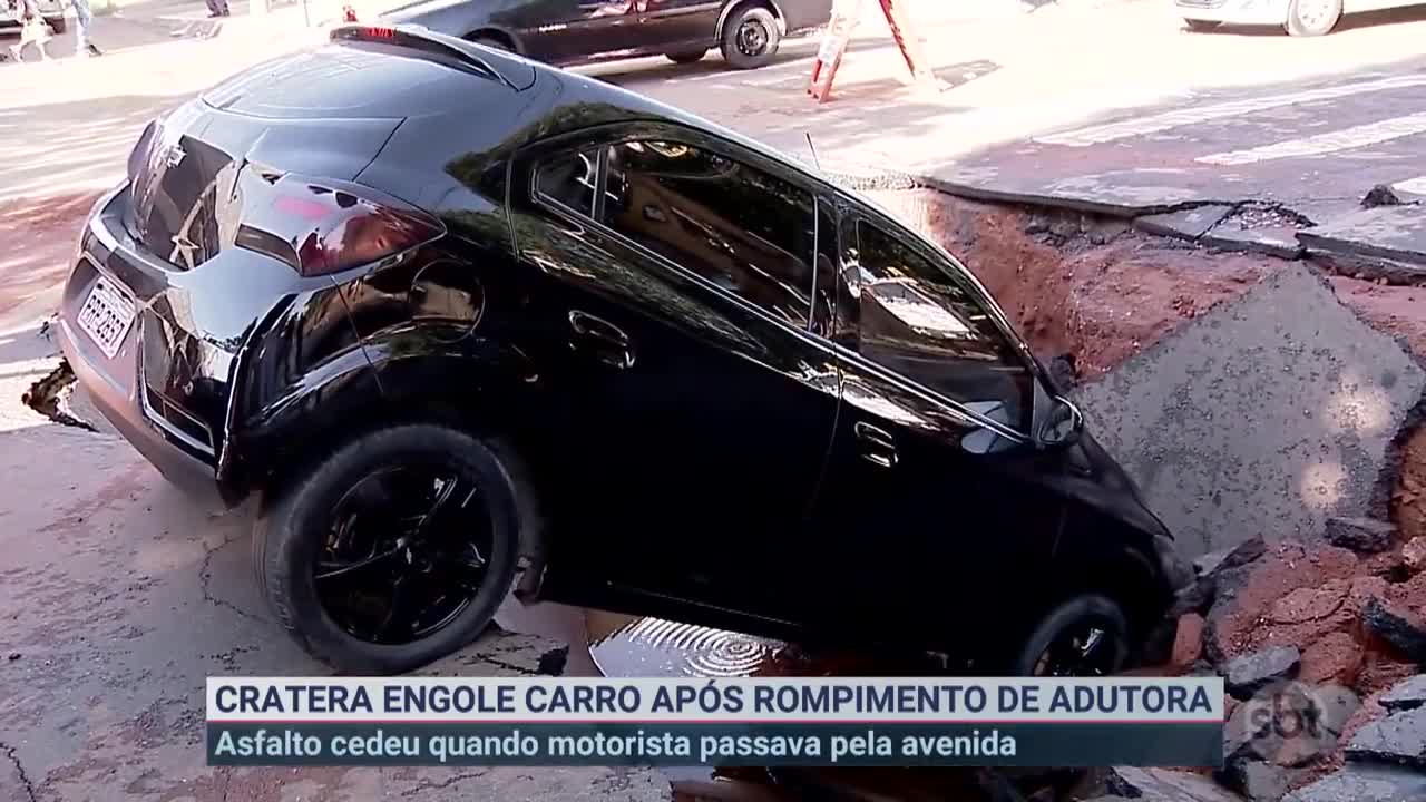 Adutora rompe e cratera engole carro em avenida